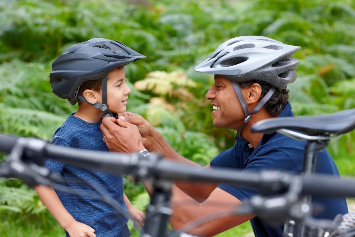 Father and young son putting on bike helmets