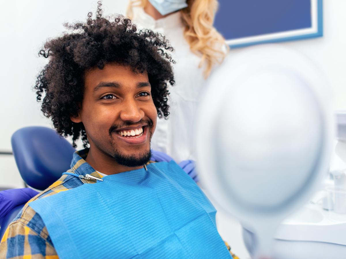 Man admiring his teeth from a dental chair