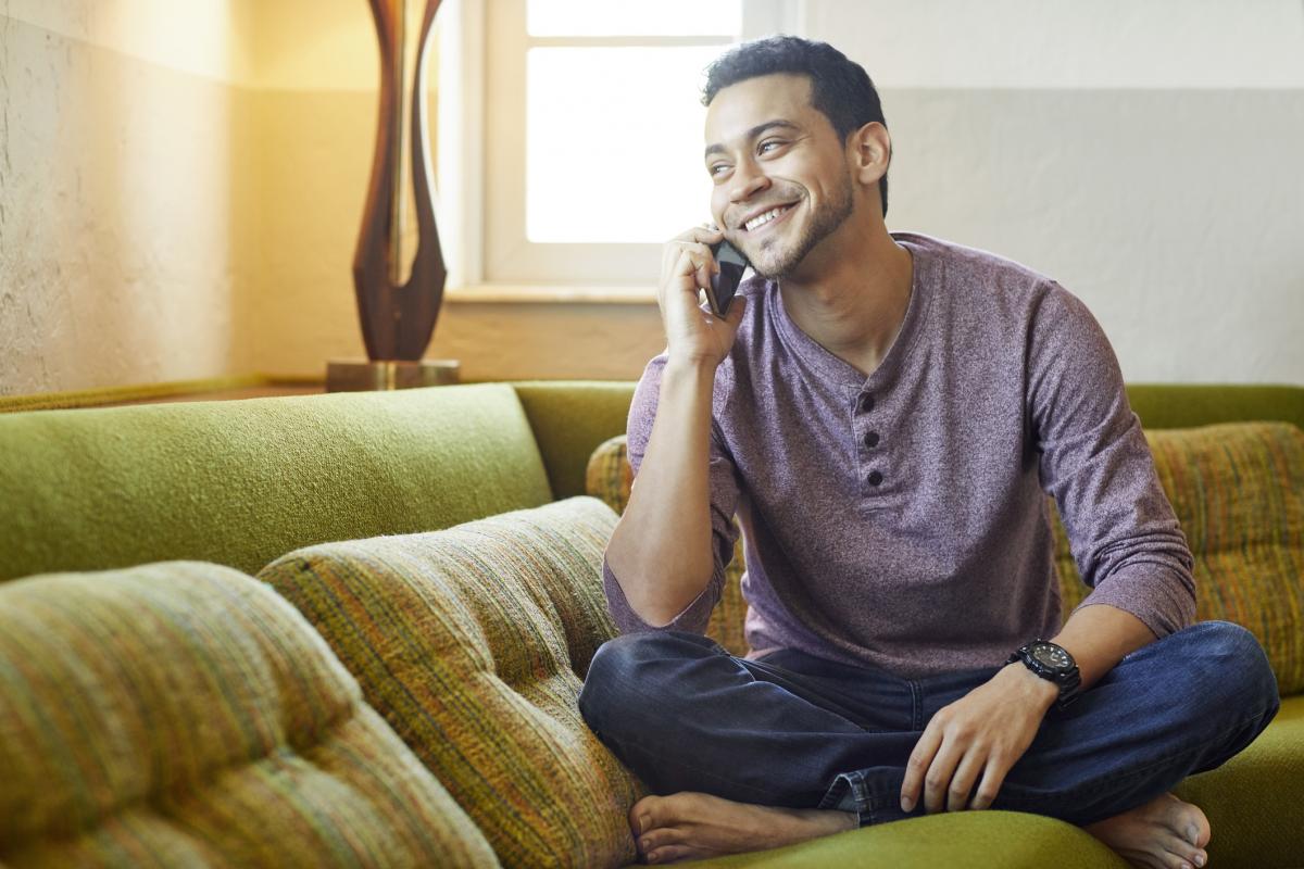 Young man sitting on the couch talking on the phone
