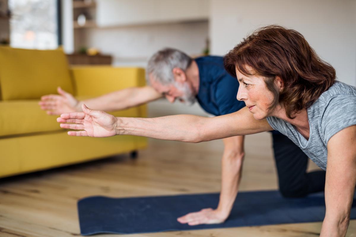 older man and woman doing yoga together
