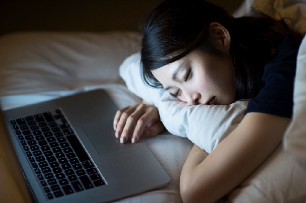 Woman sleeping with her head on her laptop