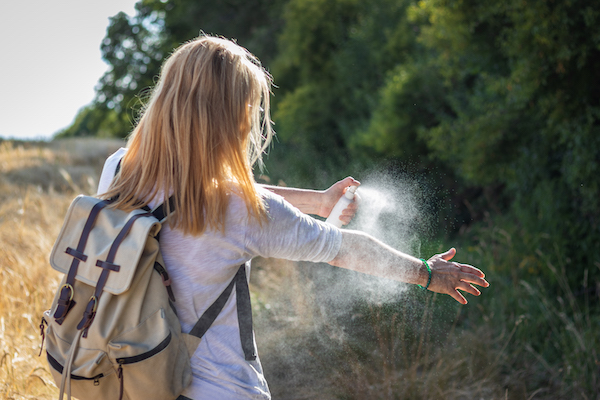 young woman applying bug spray