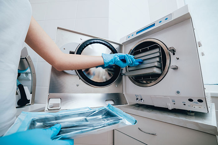 health care working inserting instruments into an autoclave