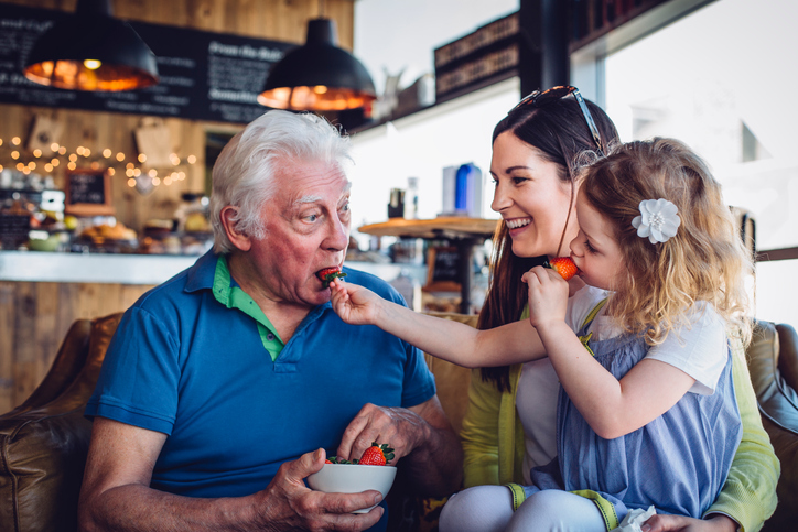 Granddaughter feeding grandfather a strawberry