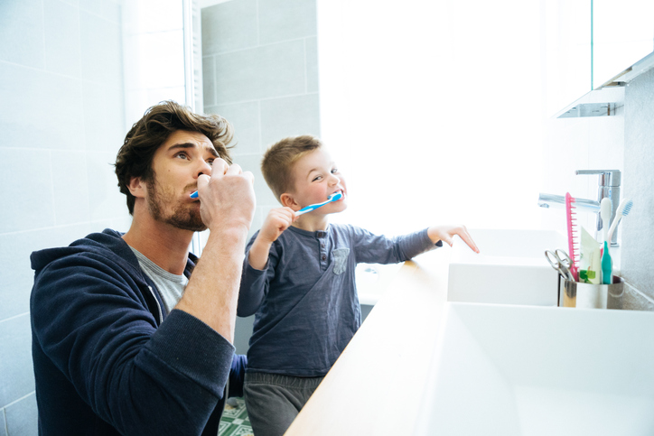 Father and son brushing teeth together