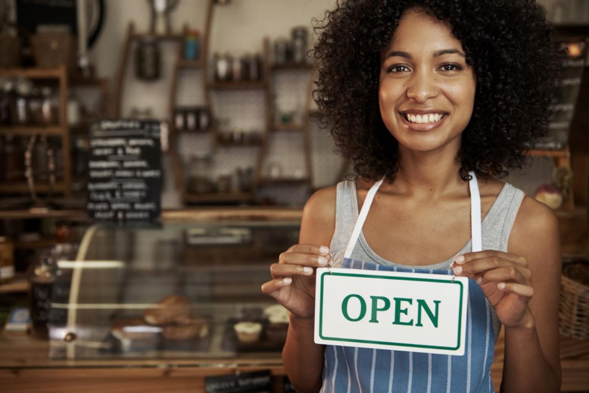 Cafe owner holding an "OPEN" sign