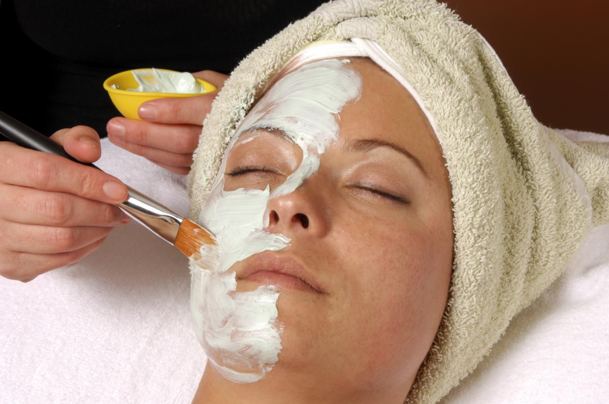 Woman getting facial mask at spa