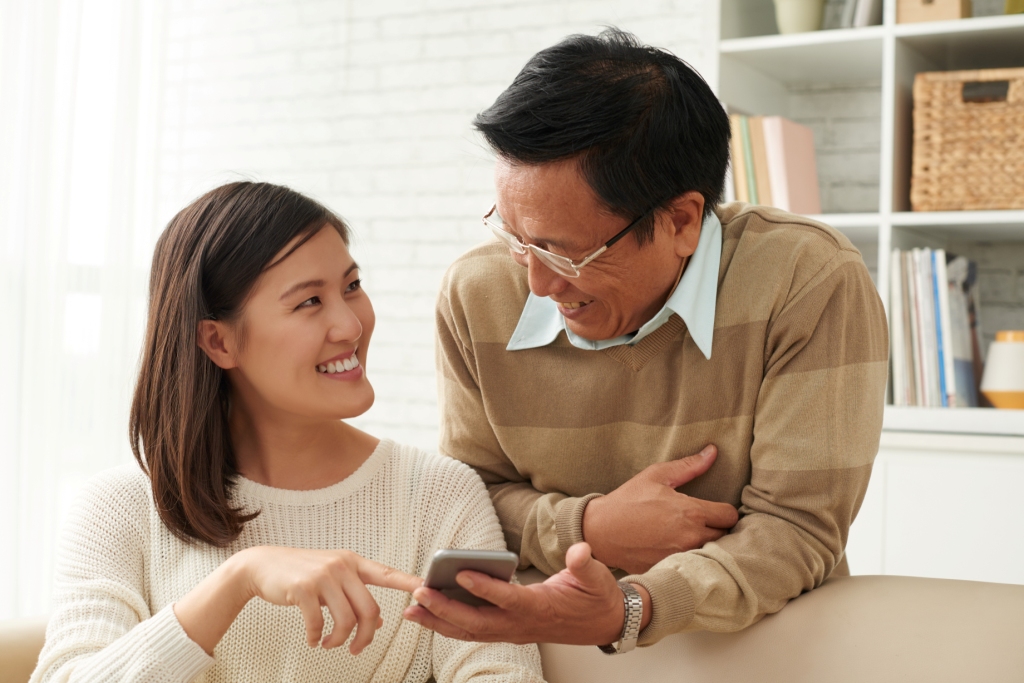 A mature father and his adult daughter looking at matches on a smartphone together