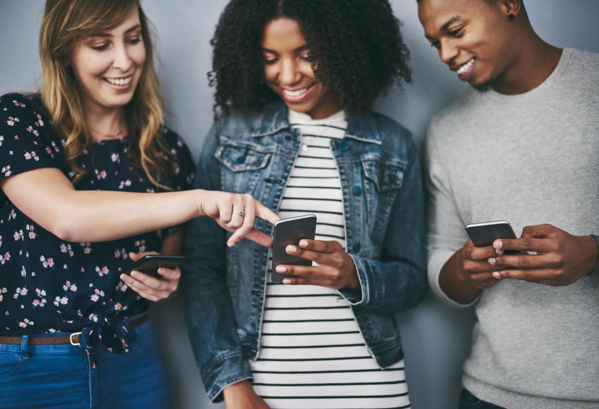 Three friends looking at their dating profiles on their smartphones together