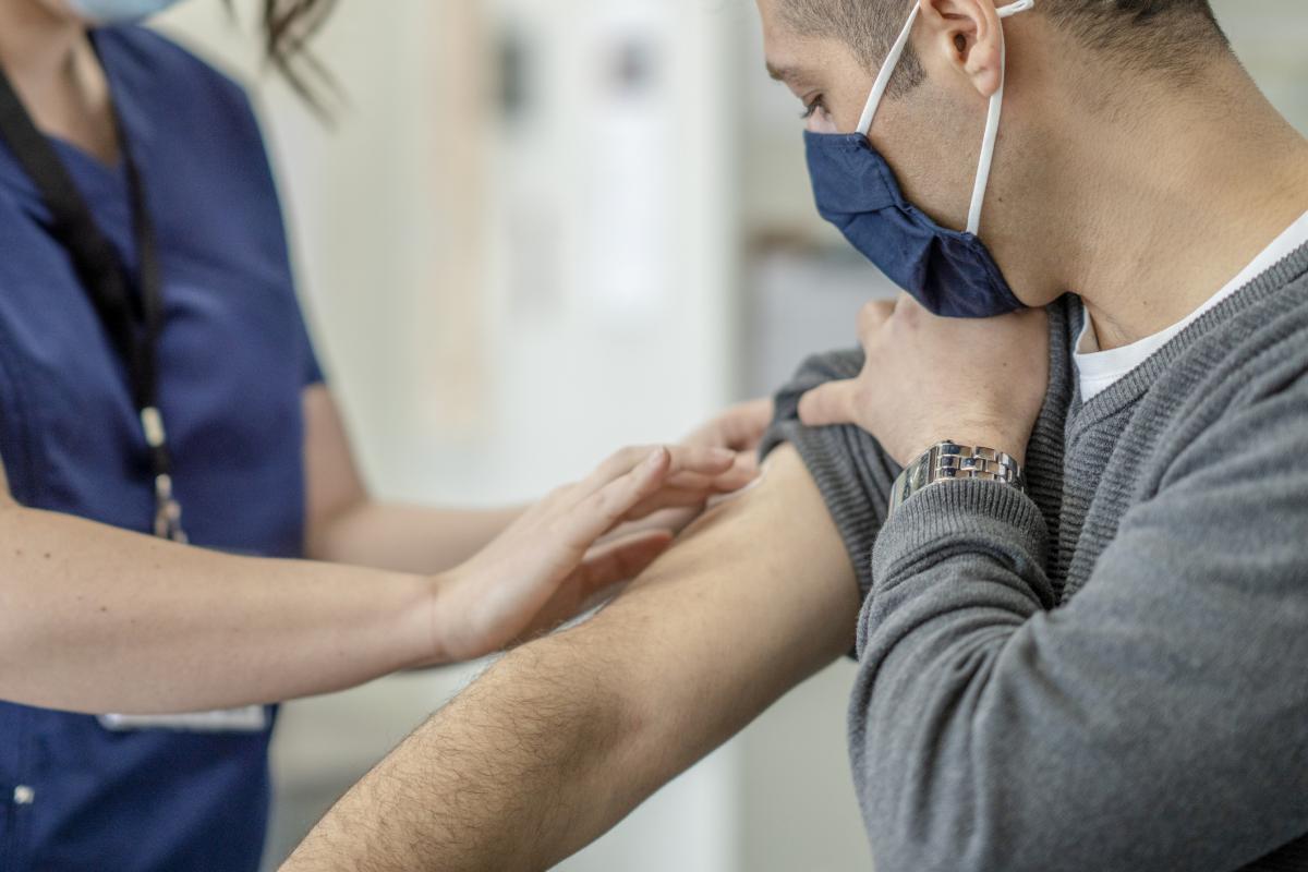 Man in face mask receives a vaccine from a female nurse