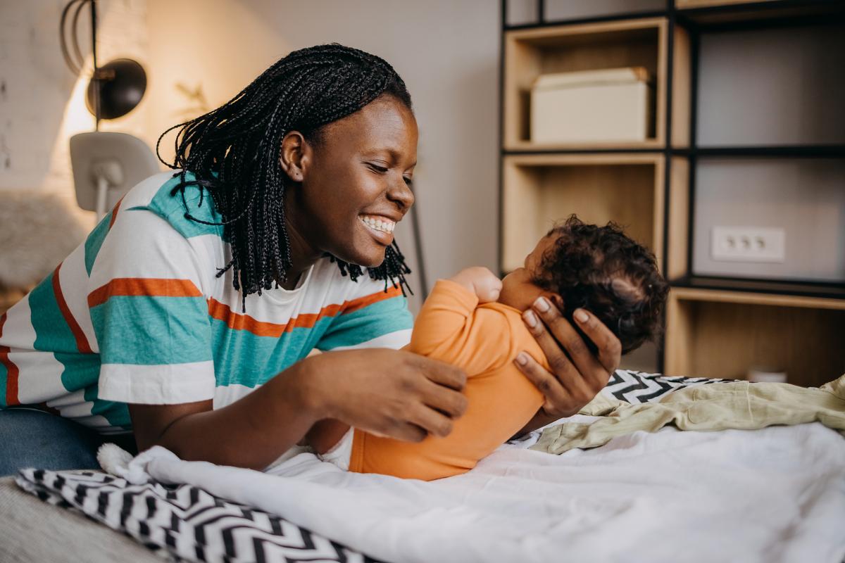 mother holding infant and looking at baby smiling