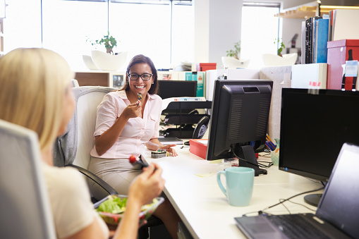 Colleagues eating lunch together at their desks