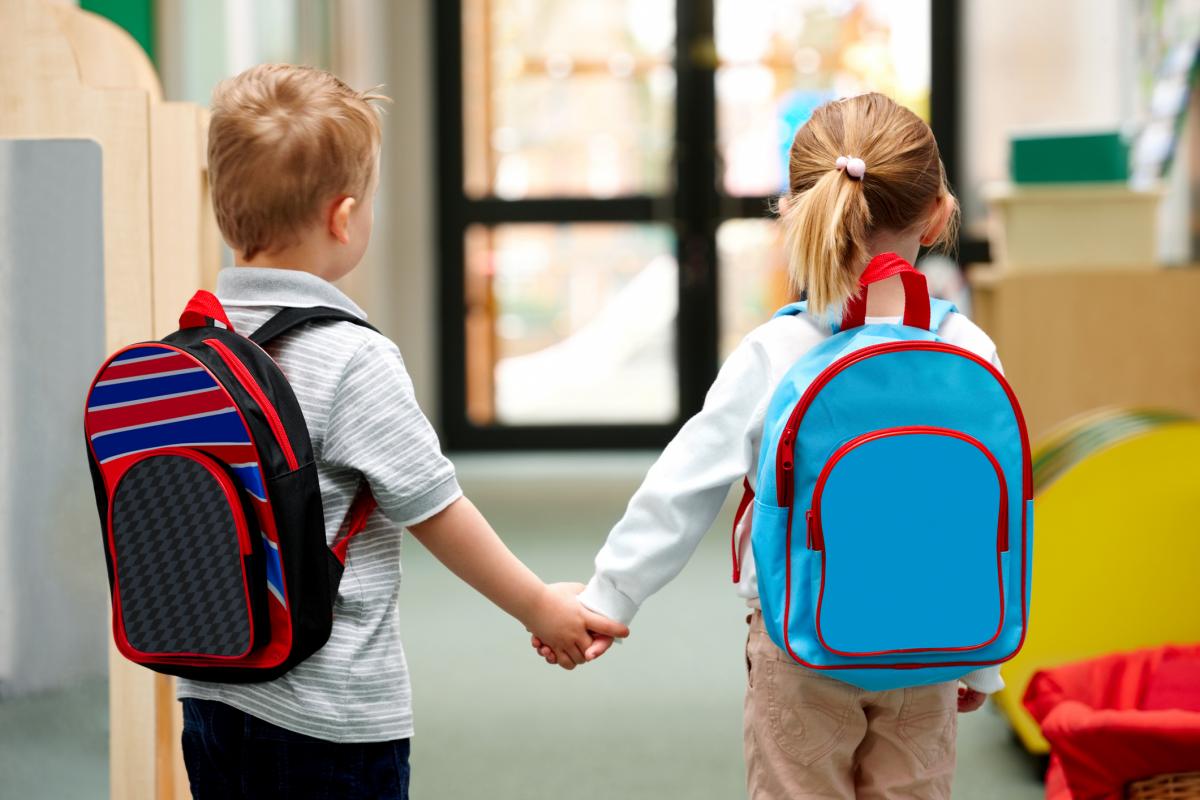 Young boy and girl with backpacks holding hands