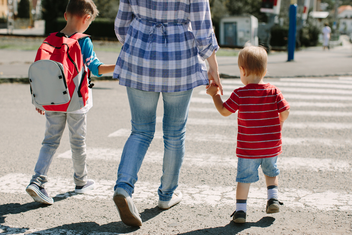 mom walking two kids across a crosswalk