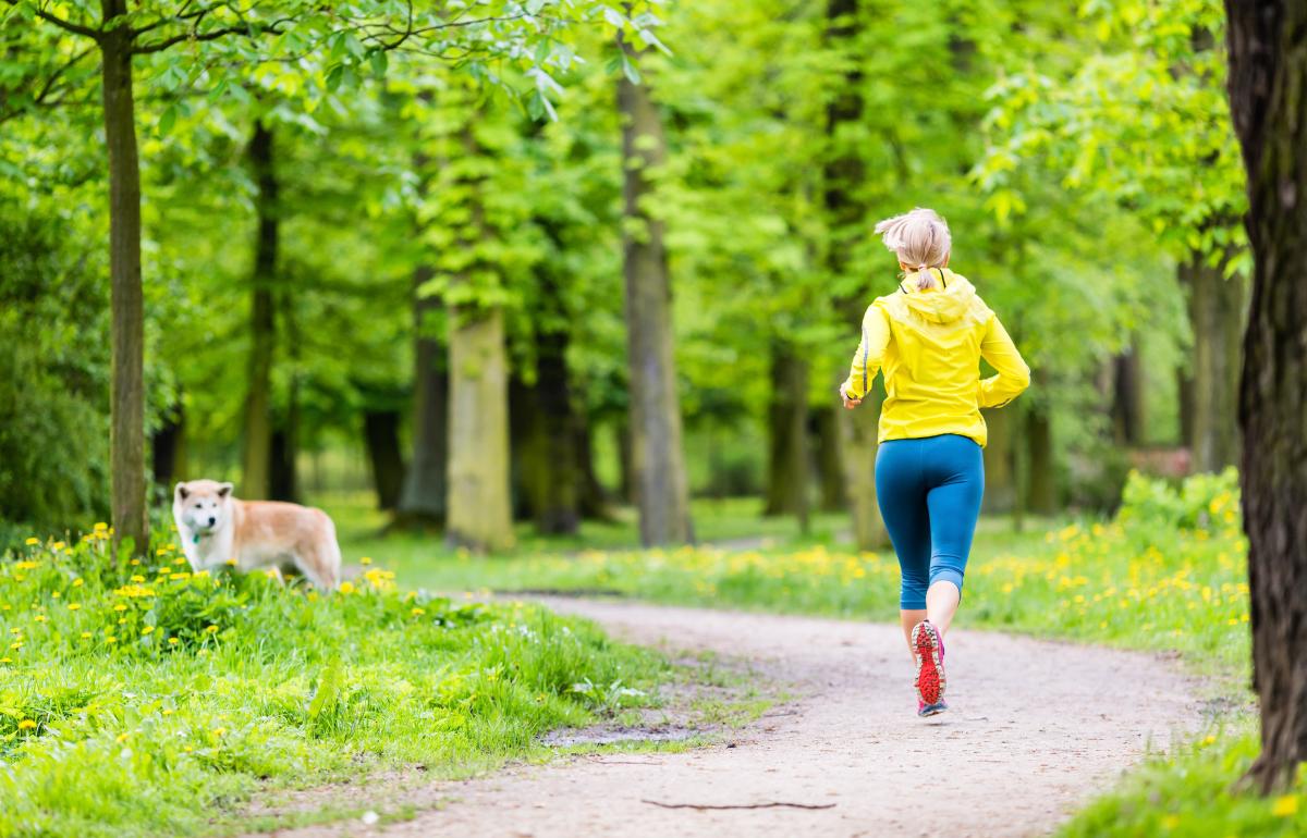 Woman running by dog in park