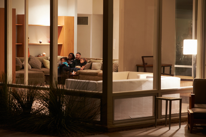 View from outside through a window of a family sitting in their living room 