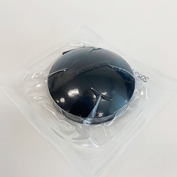 A round black radon test shrink-wrapped in plastic