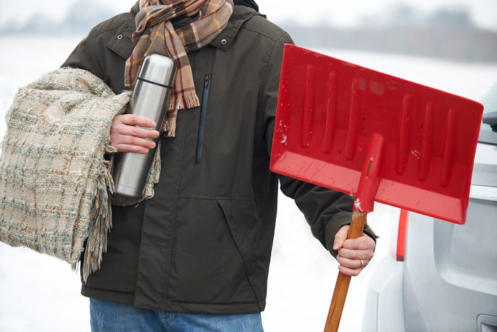 Man with shovel and blanket for winter road trip