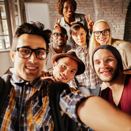 A group of colleagues in their 20's in a trendy warehouse taking a selfie 