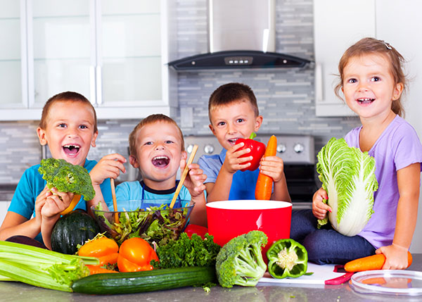 kids in a kitchen cooking with vegetables