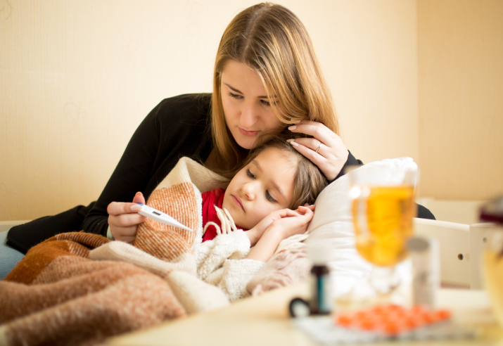 Mother checking temperature of sick daughter