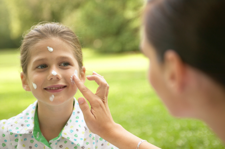 Mother putting sunscreen on girls face