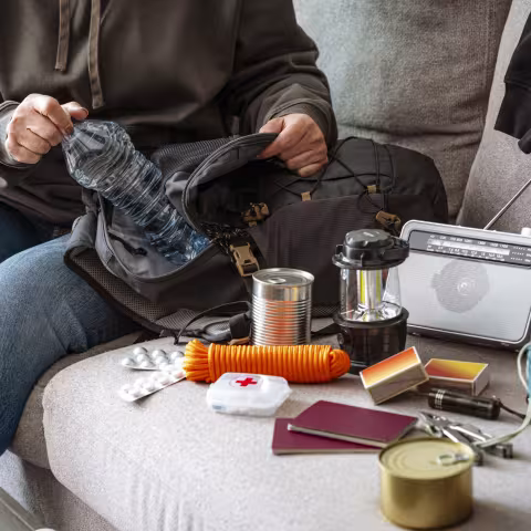 Woman filling emergency backpack with disaster emergency supplies