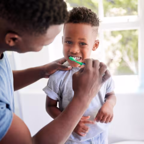 father brushing childs teeth
