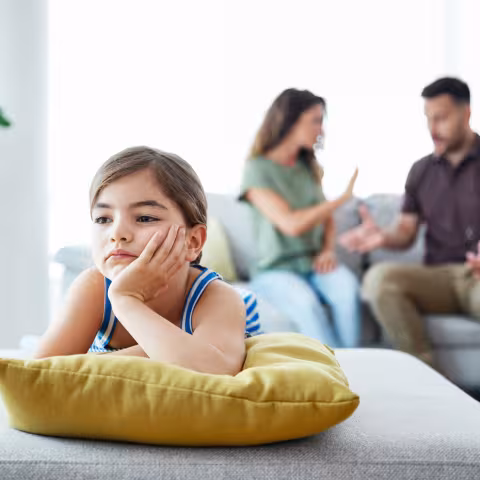 Portrait of a sad child while parents are having an argument at home