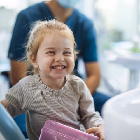Smiling young girl sitting in a dental chair in her dentists office