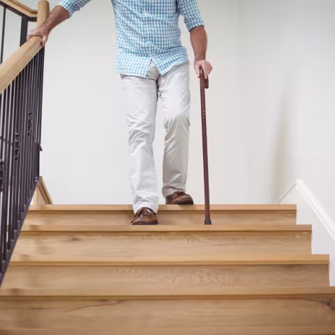 Senior man climbing downstairs with walking stick