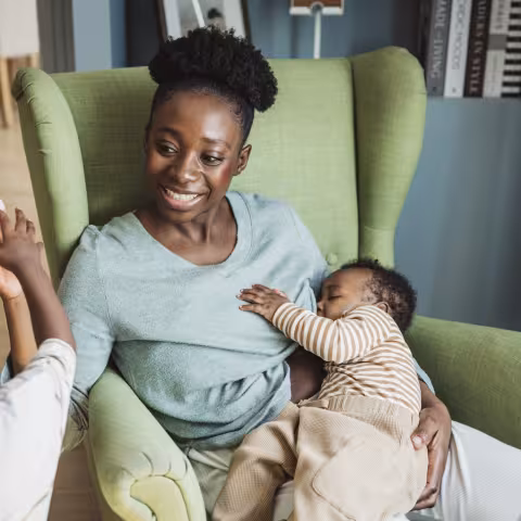 Young mother breastfeeding baby while playing with toddler