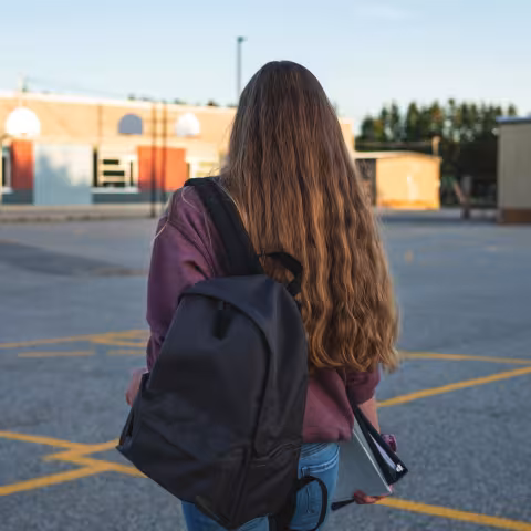 Teen girl in school parking lot, back of her