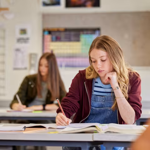 Young teen sitting in a classroom looking at her work