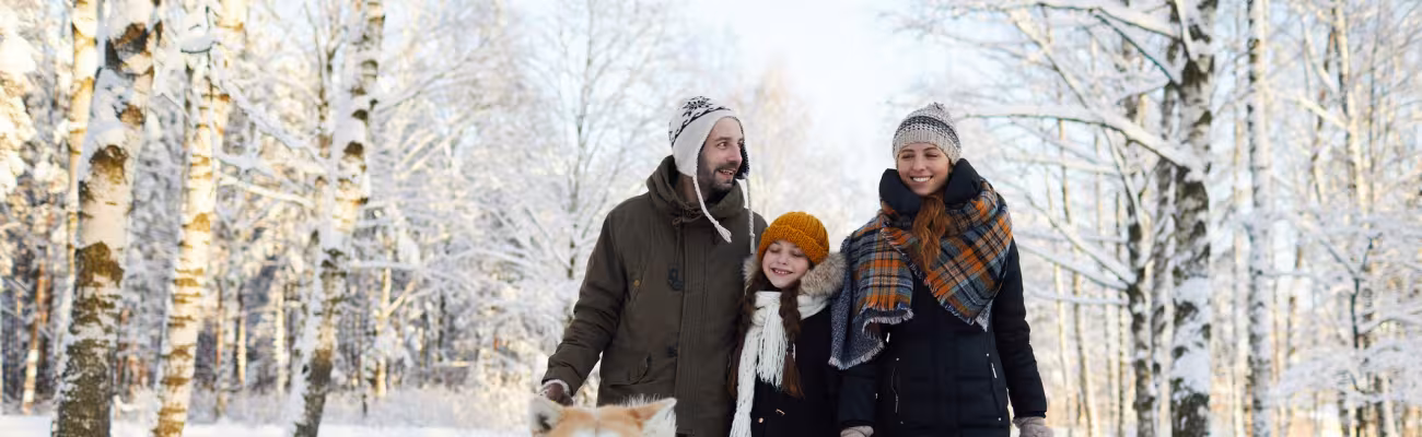 family walking in the woods with their dog in winter
