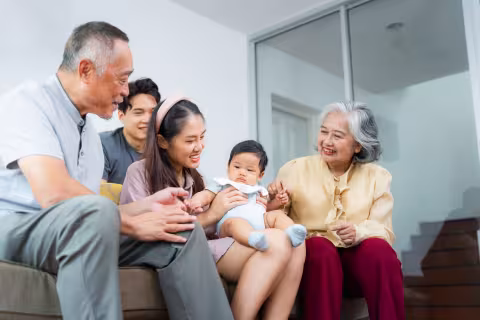 Cheerful Asian Grandparents, Parents, and Child Relaxing Together on Couch,