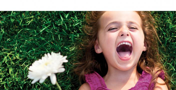 Young girl laying in the grass laughing