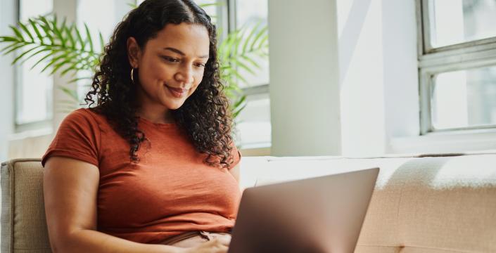 Young woman siting on couch on her laptop