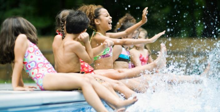Children Sitting on a outdoor pool's edge splashing and laughing
