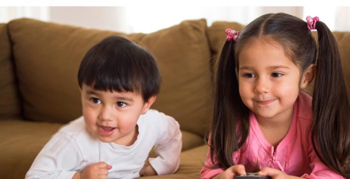 Children sitting on sofa with t.v. remote control