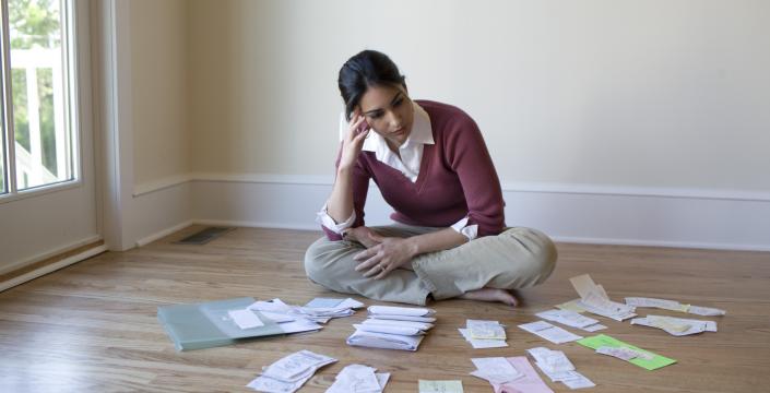 Woman sitting on floor with paperwork scattered around her