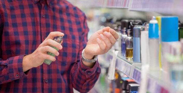 Man spraying wrist with cologne in department store