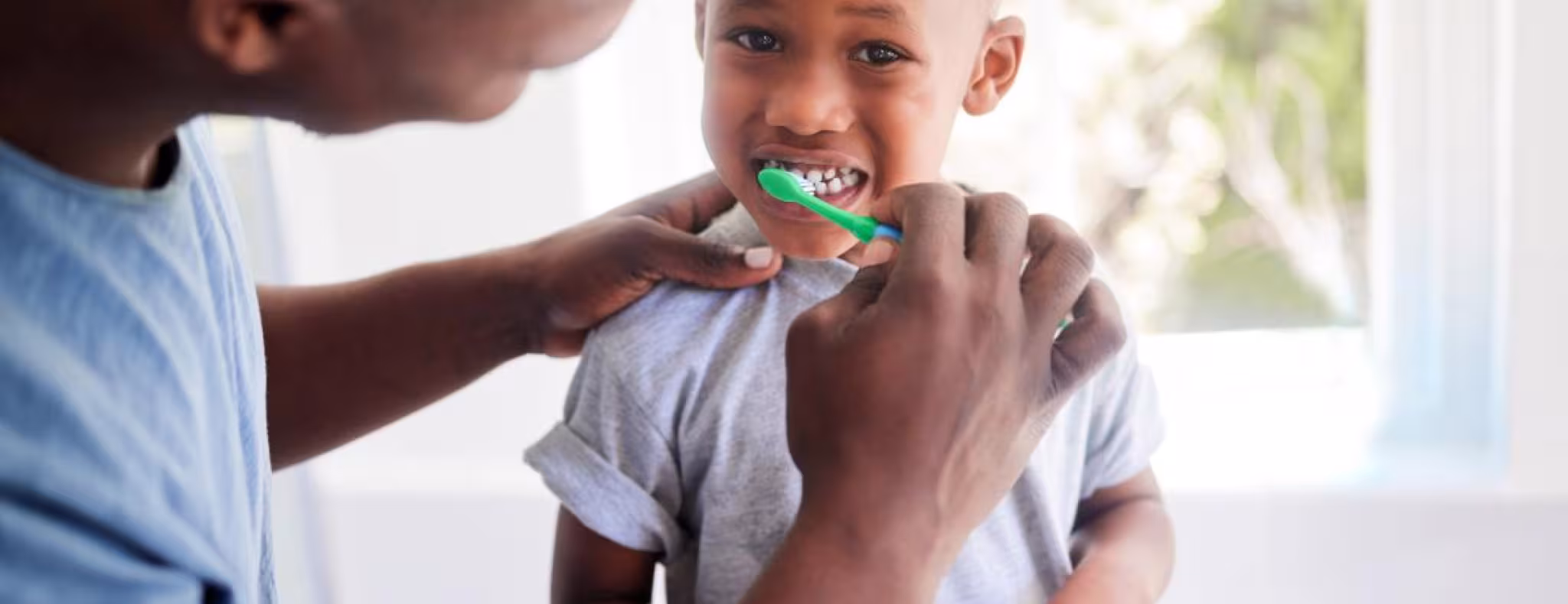 father brushing childs teeth