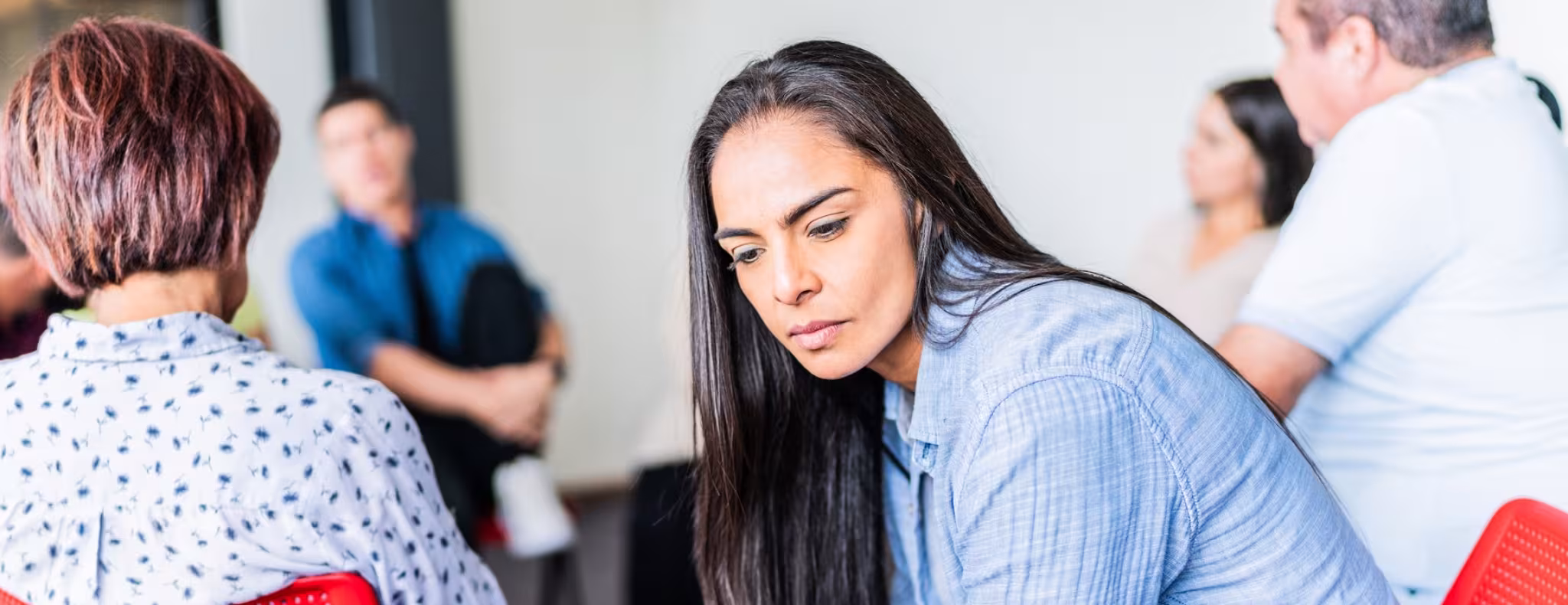 Sad adult woman during a group therapy at mental health center.