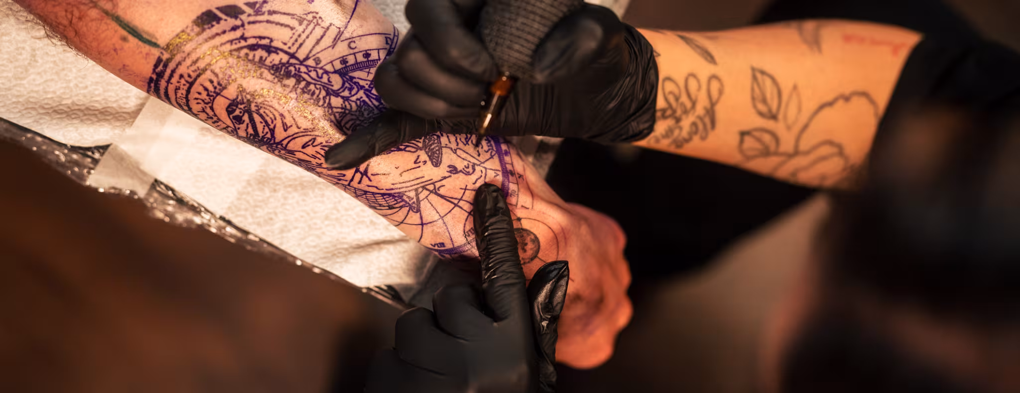 Tattoo artist inking intricate design on client's arm in a studio setting