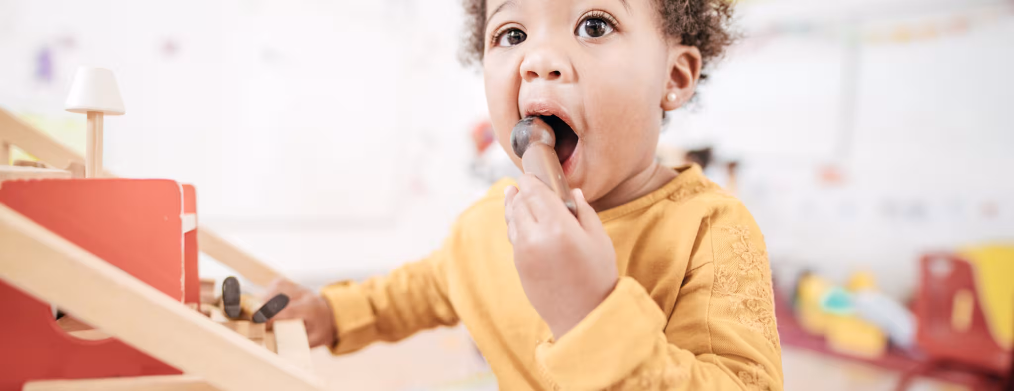 Adorable toddler indoor of a classroom putting something in his mouth