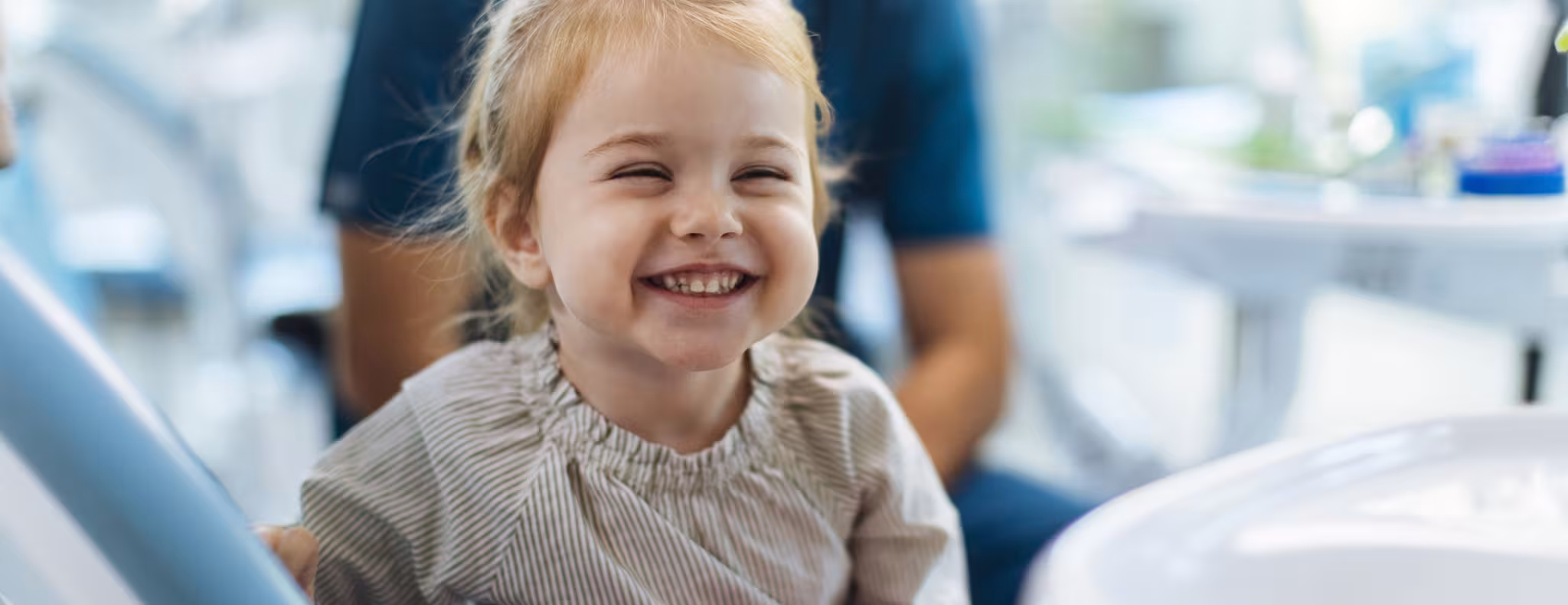 Smiling young girl sitting in a dental chair in her dentists office