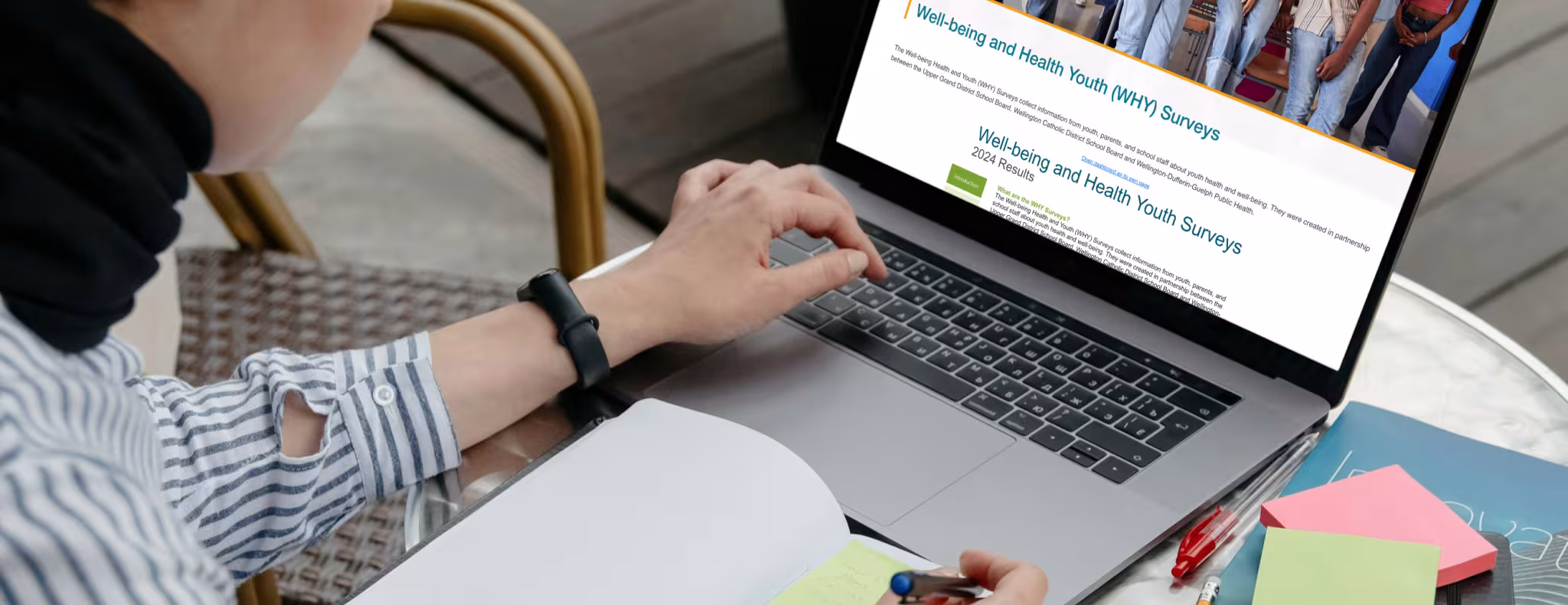Woman looking at the WHY dashboard on her laptop at a cafe outdoors