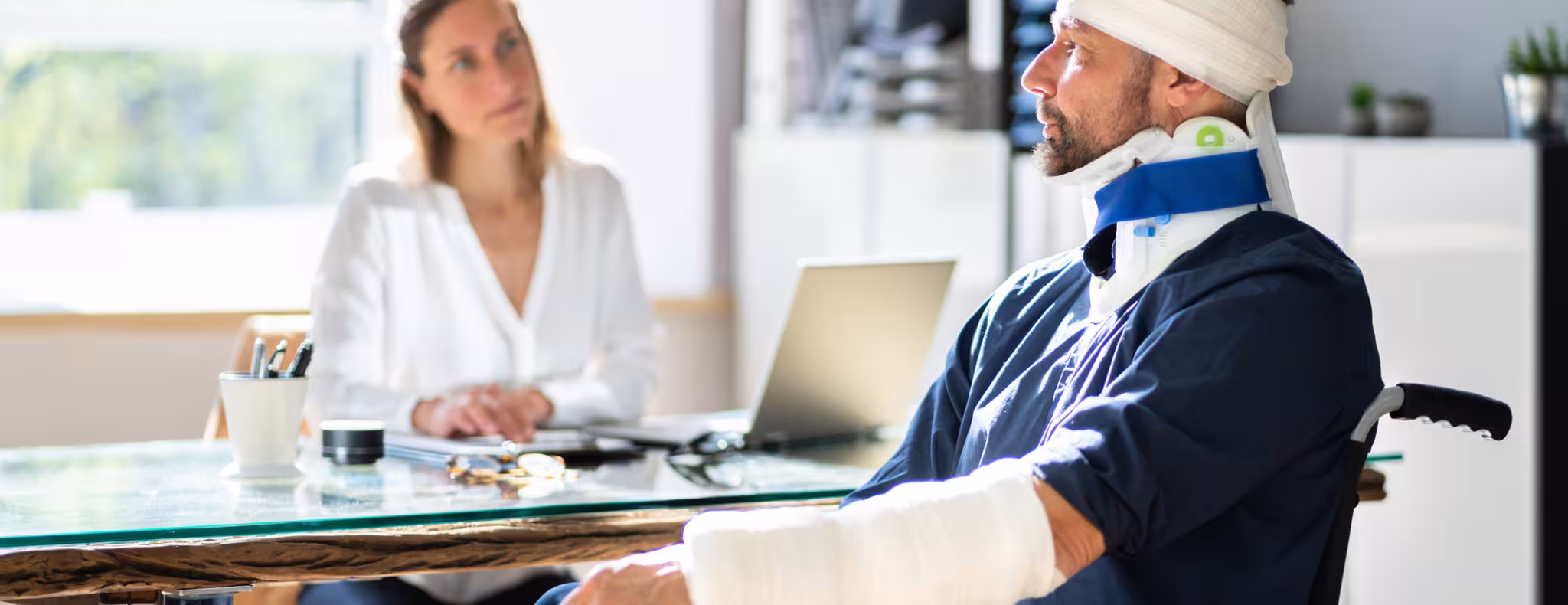 Injured man in casts and head bandages and neck brace talking to doctor