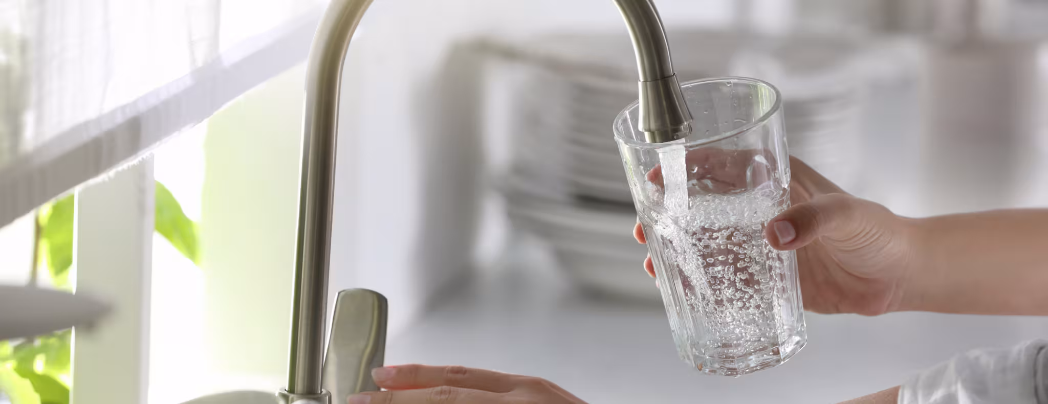 Woman running tap water into glass in kitchen